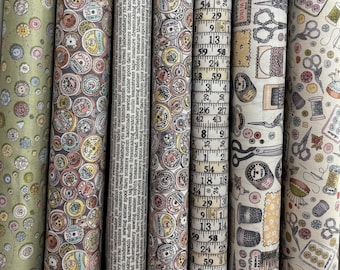 Può includere: Una collezione di rotoli di tessuto con vari motivi. I disegni includono bottoni, metri a nastro, strumenti di cucito e testo. I colori vanno dal verde e beige al grigio e rosa. I rotoli sono ben avvolti, mostrando i diversi motivi.