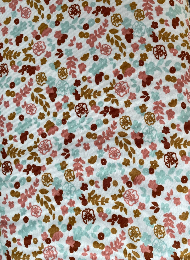 May include: White fabric with a repeating pattern of small brown, pink, and blue flowers and leaves.