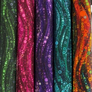 May include: A collection of fabric rolls with a repeating pattern of circles and lines in shades of green, pink, purple, teal, and orange. The fabric has a dark background and a wavy design, creating a visually appealing texture.