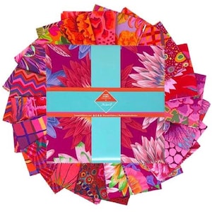 May include: A selection of patterned fabric squares in a circular arrangement. The fabrics display bright floral and abstract patterns in pink, red, orange, and purple hues. A turquoise band is wrapped around the centre, with the text "Tangerine Collective".