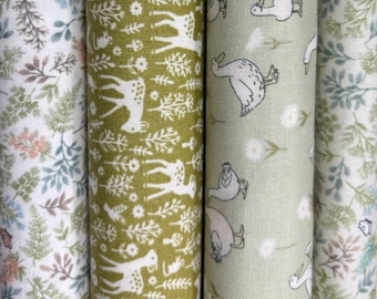 Puede incluir: Cuatro rollos de tela con diferentes patrones. Uno presenta un diseño de ciervo y árbol blanco sobre fondo verde. Otro tiene un patrón de pato sobre un fondo verde claro. Los otros dos rollos tienen patrones florales.