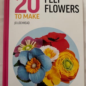 May include: The cover of a book titled "ALL-NEW 20 FELT FLOWERS TO MAKE" by Jo Lochhead. It displays a vibrant bouquet of felt flowers in red, blue, yellow, and white. Published by Search Press.