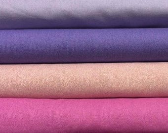 Può includere: Una pila di sei rotoli di tessuto piegati disposti orizzontalmente. I colori dall'alto verso il basso sono verde oliva, lavanda chiaro, viola medio, pesca tenue con una fine trama maculata, magenta vibrante e bordeaux scuro con trama maculata.