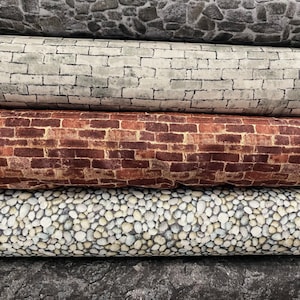 May include: Five rolls of fabric featuring various brick and stone designs. The top roll displays a grey stone pattern, the second roll shows a white brick pattern, the third roll has a red brick pattern, the fourth roll features a grey pebble pattern, and the bottom roll showcases a dark grey stone pattern.