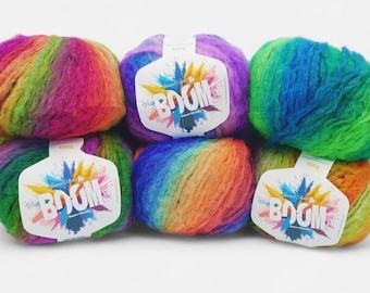 Può includere: Sei gomitoli di lana multicolore nei colori dell'arcobaleno. Ogni gomitolo ha un'etichetta con la scritta "BOOM" e un design colorato. La lana è morbida e soffice, ideale per progetti di maglia o uncinetto.