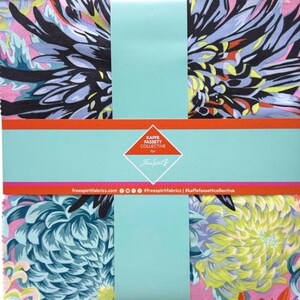 May include: A fabric bundle with colourful floral designs in pink, blue, yellow, and black. The bundle is wrapped with a light blue band and includes the text "KAFFE FASSETT COLLECTIVE". The fabric is from "freespiritfabrics.com".