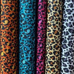 May include: Five fabric swatches featuring a leopard print design. The swatches are in orange, teal, pink, beige, and grey.