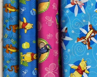 May include: Three fabric panels with different cartoon character designs. The first panel is blue with a yellow and orange tiger, the second panel is blue with a Winnie the Pooh character, and the third panel is pink with a blue donkey character.