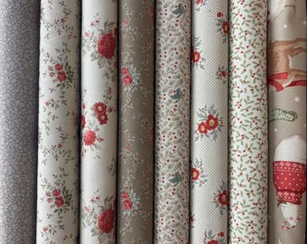 Può includere: Una collezione di rotoli di tessuto con vari motivi floreali e a tema festivo. I tessuti presentano disegni con rose rosse, uccelli e motivi invernali in tonalità di grigio, bianco e marrone. I rotoli sono ben avvolti e presentati verticalmente.