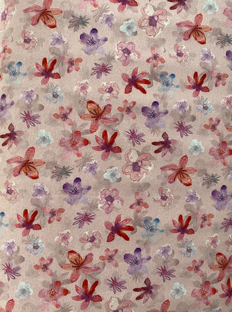 May include: A pink fabric with a floral pattern. The flowers are in shades of pink, red, and purple. The fabric has a subtle texture.