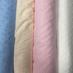 May include: Four rolls of fabric with a delicate eyelet pattern. The fabric is in shades of light blue, cream, pink, and white.
