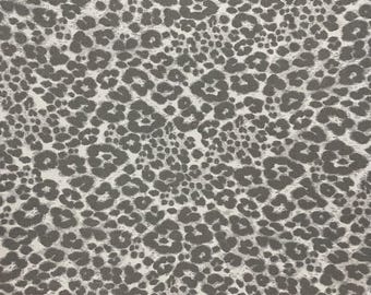Può includere: Primo piano di un tessuto bianco con un motivo a stampa animale grigio. La stampa ricorda un motivo leopardato o ghepardato.