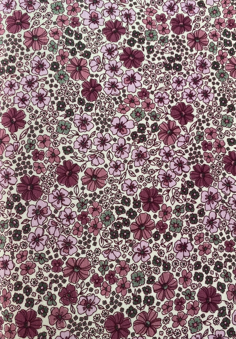 May include: A white fabric with a repeating pattern of small pink and purple flowers with green leaves. The fabric has a vintage feel.