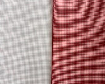 Può includere: Due pezzi di tessuto mostrati fianco a fianco. Il pezzo a sinistra presenta un motivo a micro-quadretti grigio chiaro e bianco. Il pezzo a destra presenta un motivo a micro-quadretti rosso vivace e bianco, creando un netto contrasto tra i due.