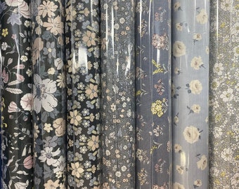 Può includere: Una collezione di sei campioni di tessuto con motivi floreali. I tessuti sono in tonalità di blu, grigio e bianco.