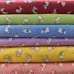 May include: Six different fabric swatches with a repeating pattern of white bunnies with pink bows on a background of white polka dots. The fabrics are in the following order from top to bottom: red, green, blue, purple, yellow, and pink.