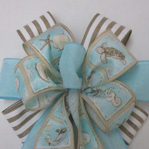 May include: A blue and brown striped ribbon bow with a blue ribbon and a ribbon with a sea life pattern. The sea life pattern includes seahorses, seashells, starfish, and sea turtles.