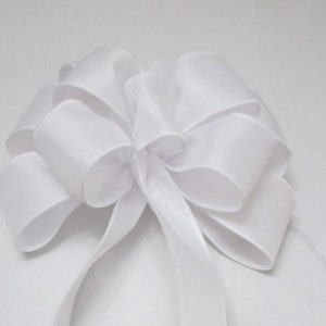 May include: A white satin bow with long tails. The bow is tied in a classic style with multiple loops and is perfect for adding a touch of elegance to any gift or occasion.