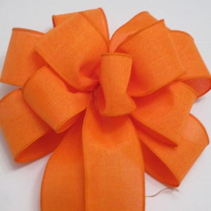 May include: A large, bright orange bow made from wired ribbon. The bow is tied with a single loop and has a long tail.