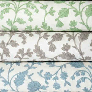 May include: Three fabric rolls with a white background and a floral pattern. The top roll has green flowers, the middle roll has gray flowers, and the bottom roll has blue flowers.