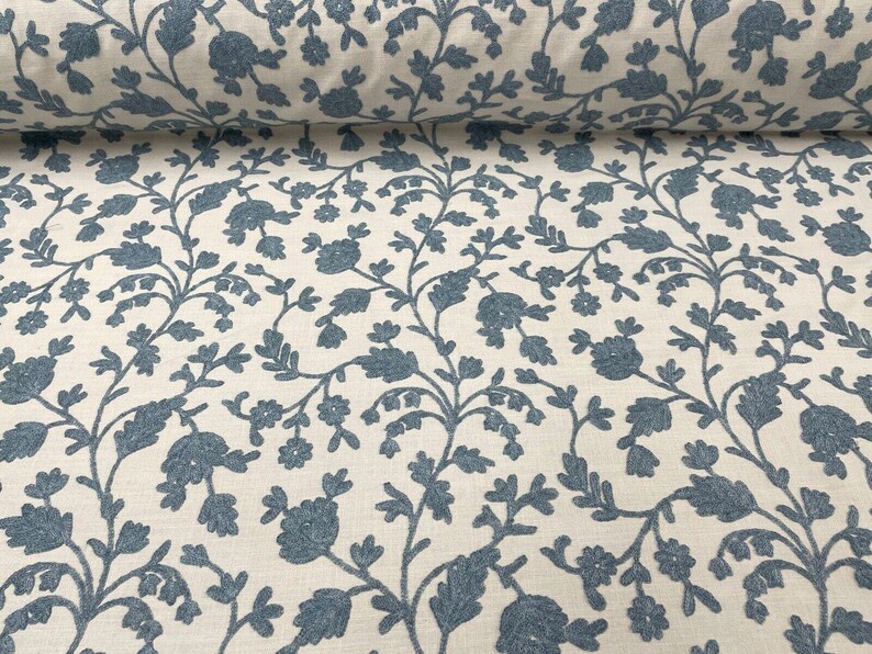 May include: White fabric with a blue floral pattern. The pattern features small blue flowers and leaves on a white background.