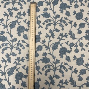 May include: A close-up of a fabric with a blue floral pattern on a white background. A ruler is placed next to the fabric to show the scale.