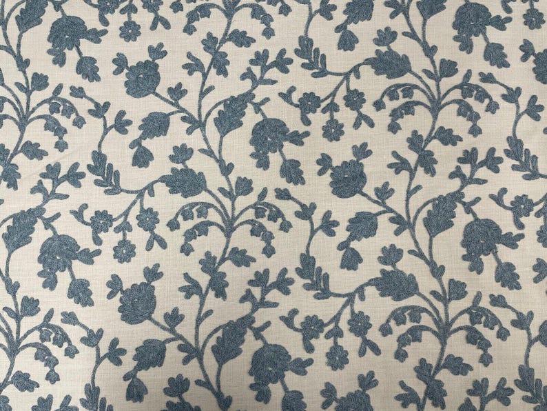 May include: A white fabric with a blue floral pattern. The pattern features small flowers and leaves in a repeating design.