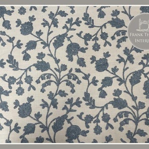 May include: A white fabric with a blue floral pattern. The pattern features small flowers and leaves, creating a delicate and intricate design. The fabric is perfect for upholstery, curtains, or other home decor projects.