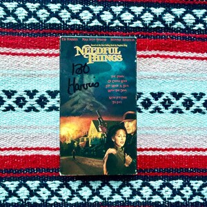 May include: A VHS tape for the movie Needful Things, based on the Stephen King novel. The tape cover features a scene from the movie with a burning house in the background. The text on the cover reads "Needful Things" and "The town of Castle Rock just made a deal with the devil. Now it's time to pay."