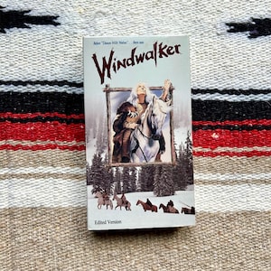 May include: A VHS tape of the movie "Windwalker" with a light blue cover. The cover features a framed image of a person on a white horse, with the title in large, stylized letters. The bottom of the tape reads "Edited Version."