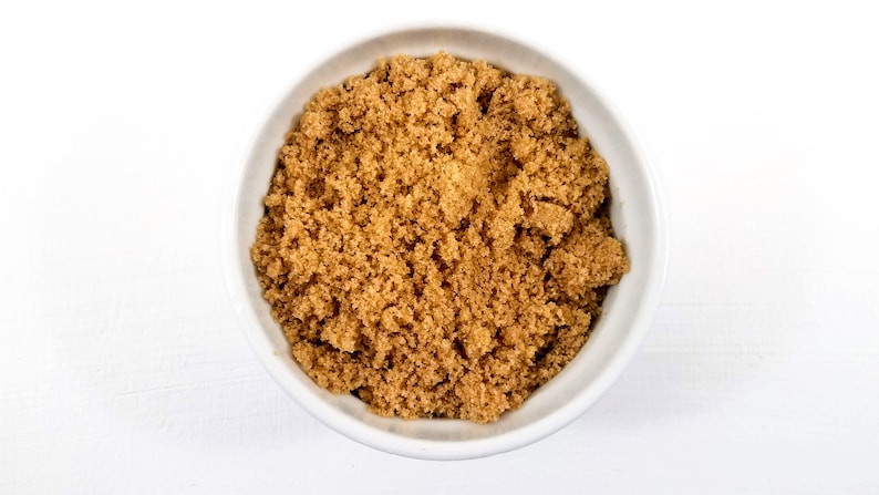 May include: A white bowl filled with brown sugar.