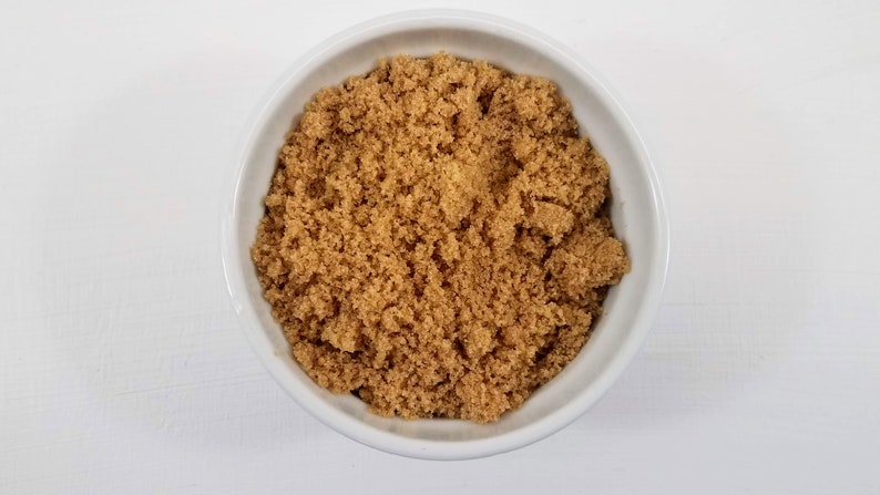 May include: A white bowl filled with brown sugar.