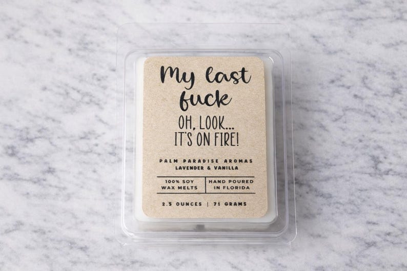 a package of a candle labeled "My last fuck oh, look... IT'S ON FIRE!" The package is placed on a marble surface.