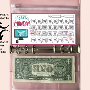 May include: A printable sheet with a pink border and the text "Cyber Monday" in a colourful font. The sheet features a grid of 36 shopping cart icons with a cursor pointing to each one. The sheet is designed to be printed and cut out for use in a planner or journal.