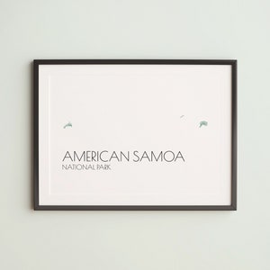 May include: Framed print featuring the words "AMERICAN SAMOA NATIONAL PARK" in a minimalist design. The print has a white background with a black frame. The print includes a map of the American Samoa islands in green.