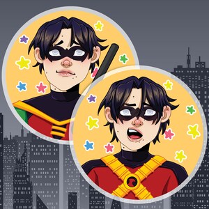Op de afbeelding: Twee illustraties van Robin, een superheld uit het DC Comics-universum. Beide afbeeldingen tonen Robin in een rood-geel kostuum met een zwart masker en een rood 'R'-symbool op zijn borst. De achtergrond van elke afbeelding is een gele cirkel met kleurrijke sterren.