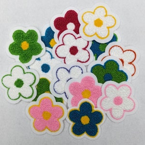 May include: A collection of 12 colorful felt flower patches with embroidered details. The flowers are in various colors, including red, green, blue, yellow, and white.