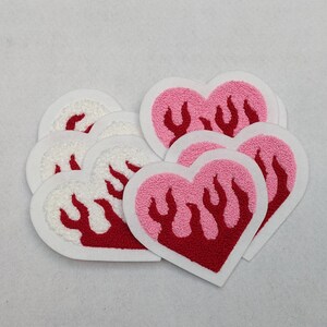 Könnte beinhalten: Ein Set mit fünf Bügelbildern in Herzform mit roten Flammen auf rosa und weißem Hintergrund.