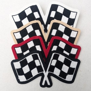 Pode incluir: Uma coleção de patches bordados com bandeiras quadriculadas em preto e branco, com bordas vermelhas ou bege. Os patches estão dispostos em um padrão em camadas, sugerindo um tema de corrida ou automobilismo.
