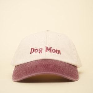 Könnte beinhalten: Baseballcap mit cremefarbener Krone und weinrotem Schirm. Die Worte "Dog Mom" sind in Weinrot auf die Vorderseite der Kappe gestickt. Ein lässiges Accessoire.