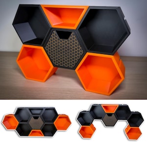 May include: A modular shelf unit with a geometric honeycomb design. The unit features hexagonal compartments in black and bright orange, with a central section showcasing a honeycomb pattern. The unit is designed to be freestanding.