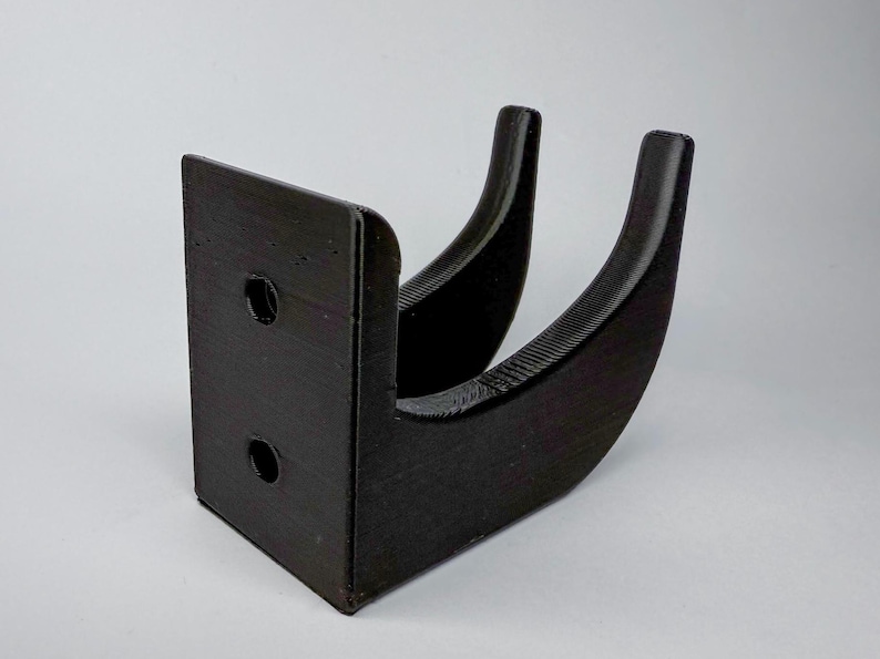 Puede incluir: Soporte de pared de pl&aacute;stico negro con dos ganchos. El soporte tiene dos agujeros para tornillos en la parte posterior.