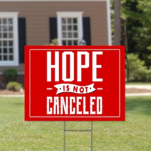 May include: Red yard sign with white text that reads "HOPE IS NOT CANCELED".
