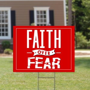 May include: Red yard sign with white text that reads "FAITH OVER FEAR".