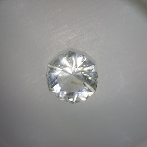 May include: A clear, faceted gemstone with a hexagonal shape.