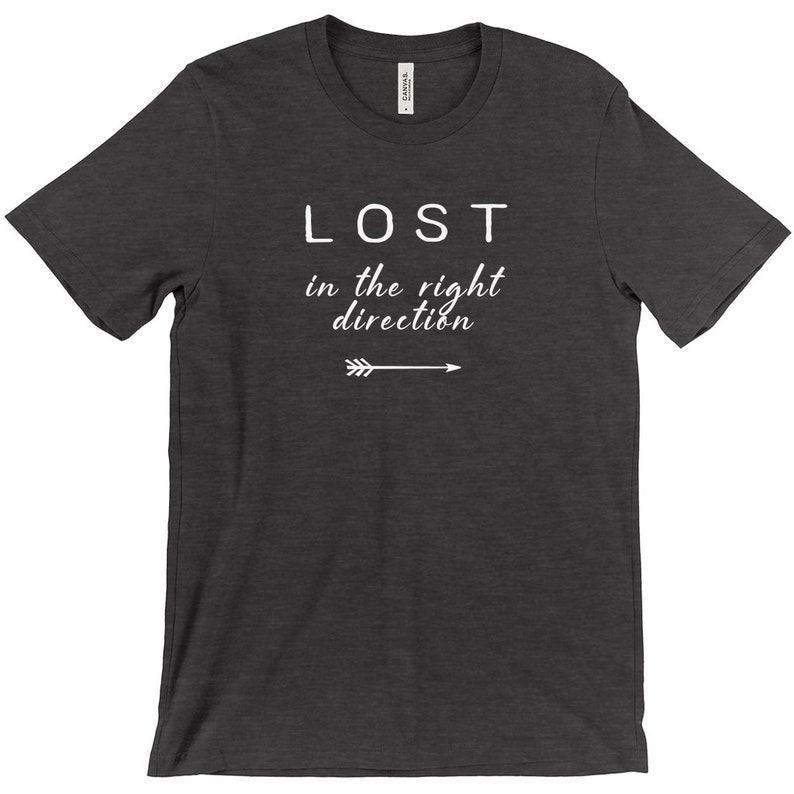 May include: Dark gray t-shirt with the white text "LOST in the right direction" and an arrow pointing right. The shirt is made of a soft material and has short sleeves.