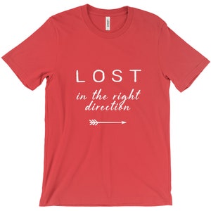 May include: Red t-shirt with the white text "LOST in the right direction" and an arrow pointing right. The shirt is made of a soft material.