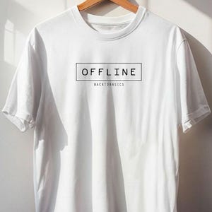Puede incluir: Una camiseta blanca de manga corta que presenta un contorno rectangular negro con la palabra OFFLINE en letras mayúsculas, con el texto BACKTOBASICS impreso en una fuente más pequeña justo debajo del rectángulo en el pecho.