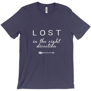 May include: A navy blue t-shirt with the words "LOST" above "in the right direction" in white, with a white arrow pointing right. The shirt is made of a soft material.