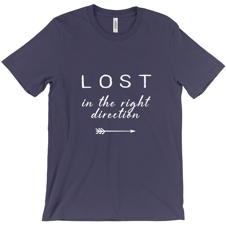 May include: A navy blue t-shirt with the words "LOST" above "in the right direction" in white, with a white arrow pointing right. The shirt is made of a soft material.